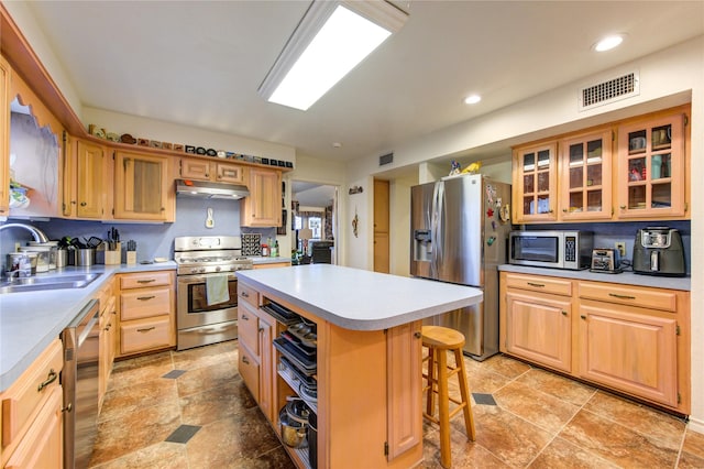 kitchen with sink, decorative backsplash, a kitchen island, a kitchen bar, and stainless steel appliances