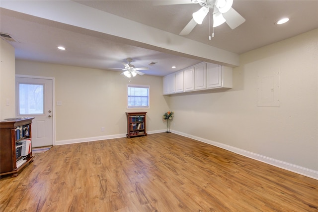 unfurnished living room with electric panel, ceiling fan, and light hardwood / wood-style floors