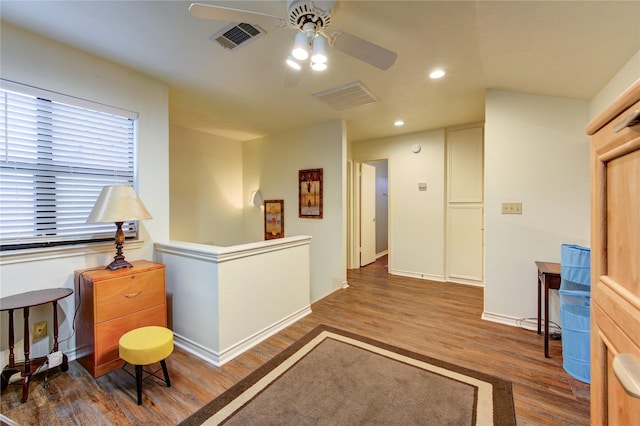 living area featuring ceiling fan and dark wood-type flooring