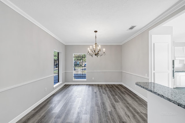 unfurnished dining area featuring a chandelier, a textured ceiling, dark wood-type flooring, and crown molding