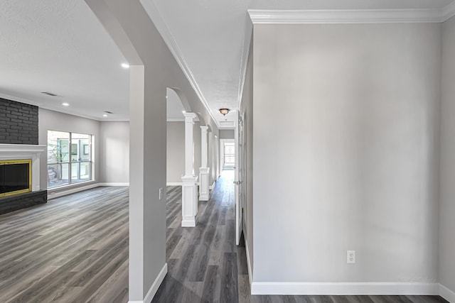 hallway with ornate columns, dark hardwood / wood-style floors, and ornamental molding