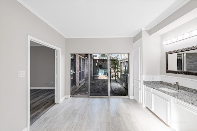 interior space with sink, light wood-type flooring, and ornamental molding