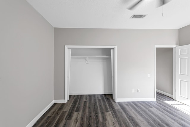 unfurnished bedroom with a textured ceiling, a closet, dark hardwood / wood-style floors, and ceiling fan