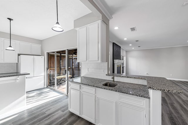 kitchen with white cabinets, white fridge, sink, and hanging light fixtures