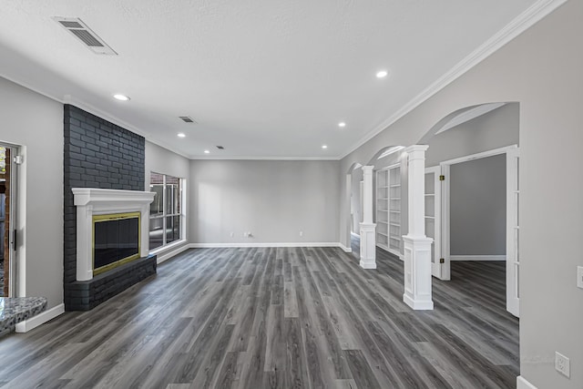 unfurnished living room featuring ornate columns, a textured ceiling, crown molding, a fireplace, and dark hardwood / wood-style floors