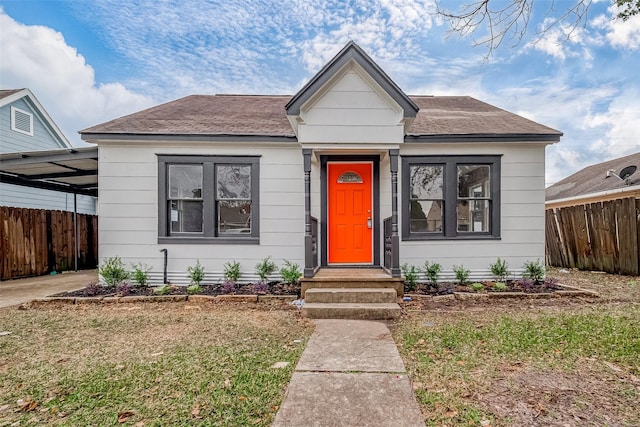 bungalow-style house featuring a front lawn and a carport