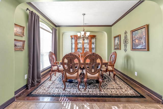 dining space featuring dark tile patterned floors, ornamental molding, a wealth of natural light, and an inviting chandelier