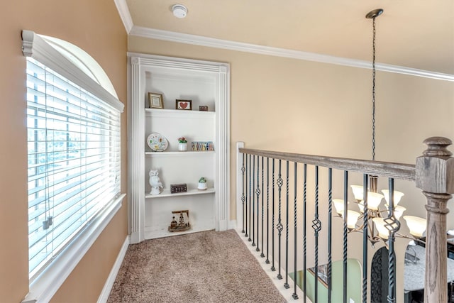 hall with carpet flooring, ornamental molding, and a notable chandelier