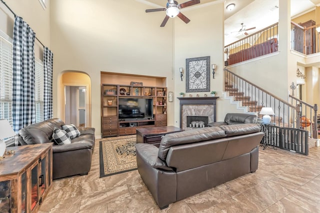 living room with a fireplace, a high ceiling, and ceiling fan