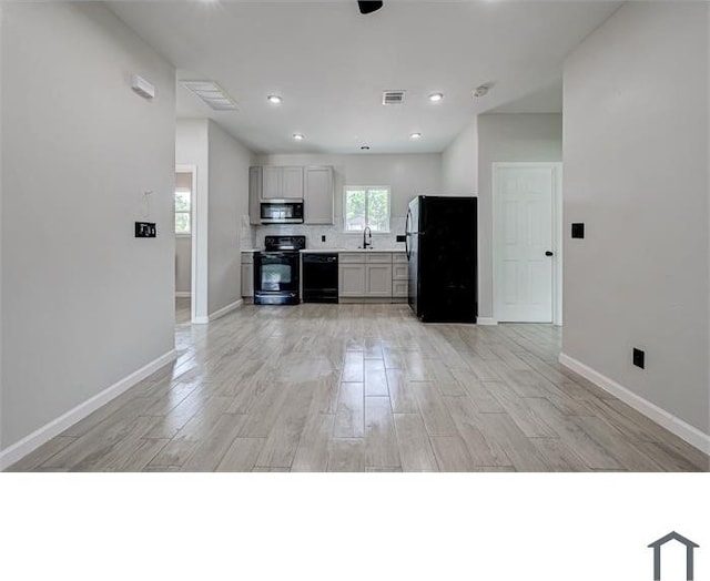 kitchen with decorative backsplash, light wood-type flooring, sink, black appliances, and gray cabinets