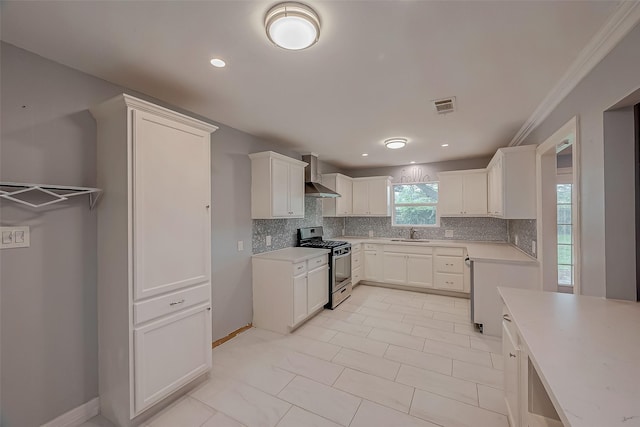 kitchen with white cabinets, sink, gas range, wall chimney exhaust hood, and tasteful backsplash