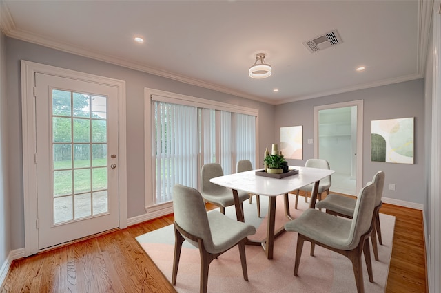 dining area with light hardwood / wood-style floors and crown molding