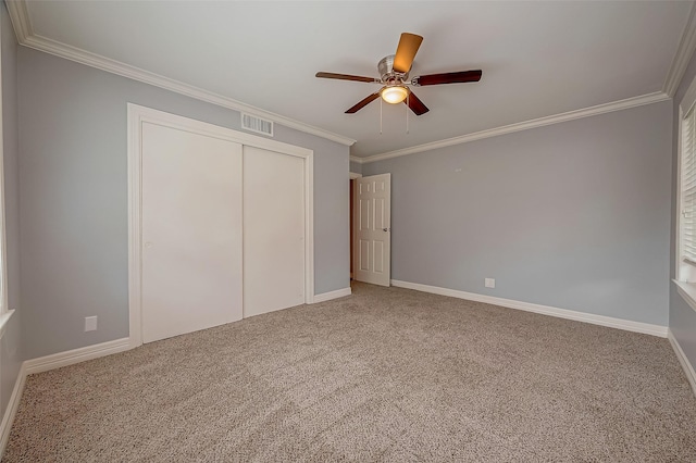 unfurnished bedroom featuring carpet flooring, ceiling fan, a closet, and ornamental molding