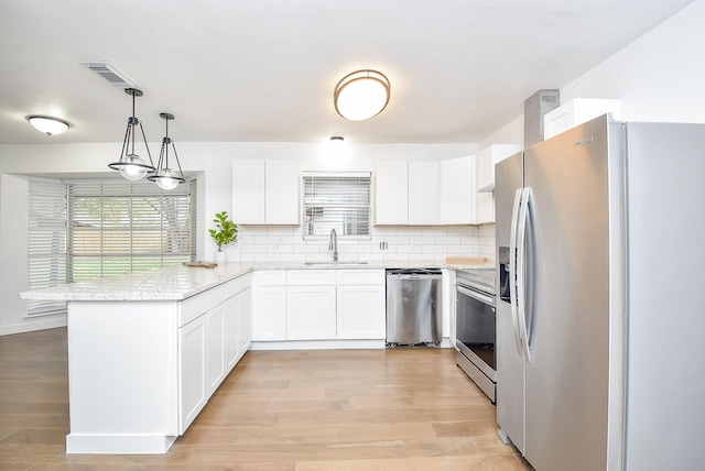 kitchen with white cabinetry, sink, pendant lighting, decorative backsplash, and appliances with stainless steel finishes