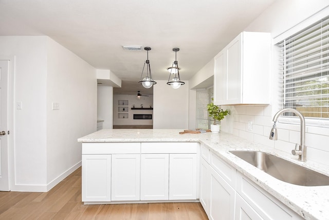 kitchen with kitchen peninsula, pendant lighting, white cabinetry, and sink