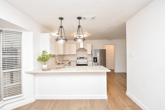 kitchen with sink, stainless steel appliances, tasteful backsplash, kitchen peninsula, and decorative light fixtures