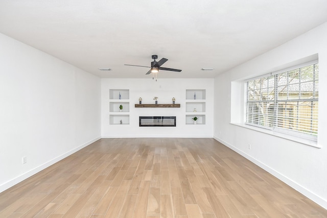 unfurnished living room with ceiling fan, built in features, and light hardwood / wood-style flooring