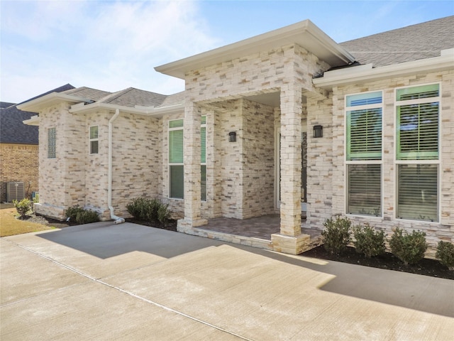 view of exterior entry with a patio and central AC