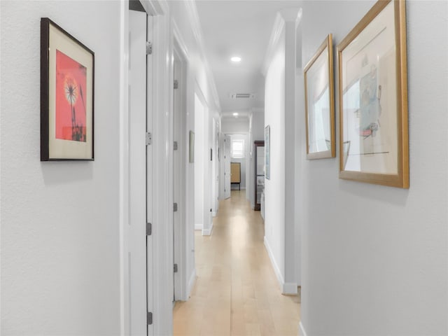 corridor featuring light wood-type flooring and ornamental molding