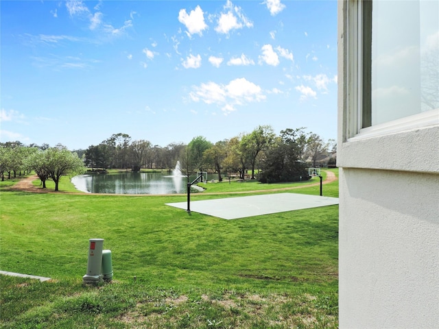 exterior space featuring a water view, basketball hoop, and a lawn