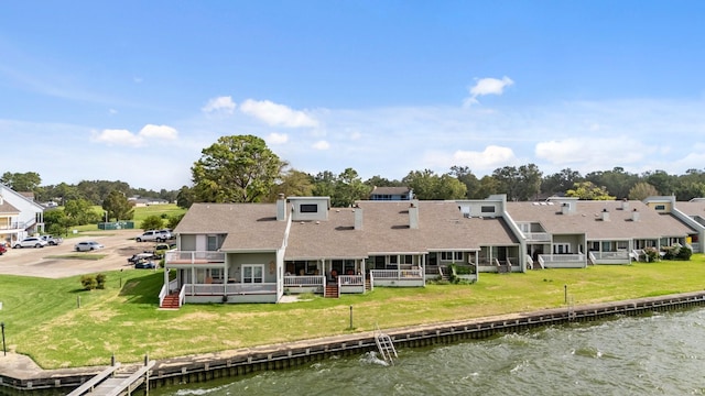 rear view of house with a deck with water view and a yard