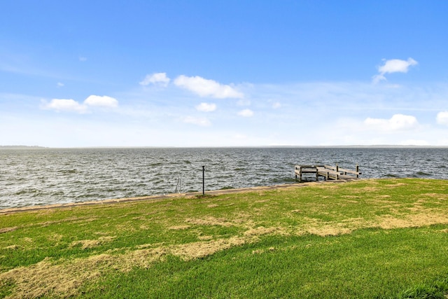 view of dock with a water view and a lawn