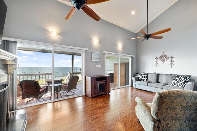 living room with hardwood / wood-style flooring, ceiling fan, a water view, and high vaulted ceiling