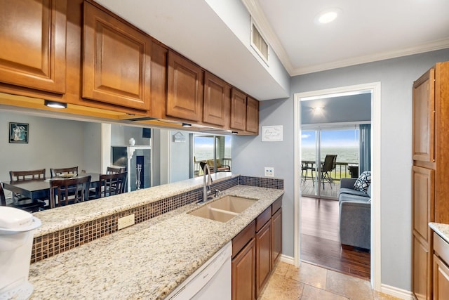 kitchen with light tile patterned floors, light stone counters, ornamental molding, and sink