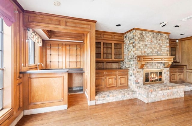 bar with a fireplace, light wood-type flooring, and ornamental molding