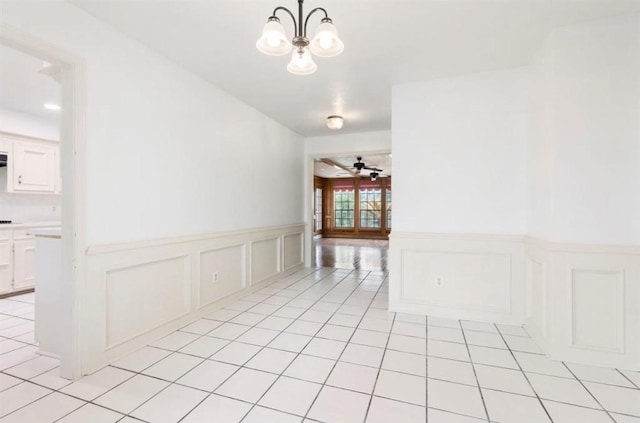 unfurnished room featuring light tile patterned floors and ceiling fan with notable chandelier