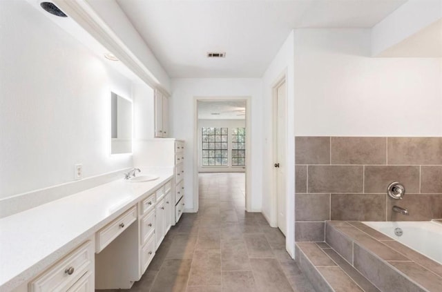 bathroom with tile patterned flooring, vanity, and a relaxing tiled tub