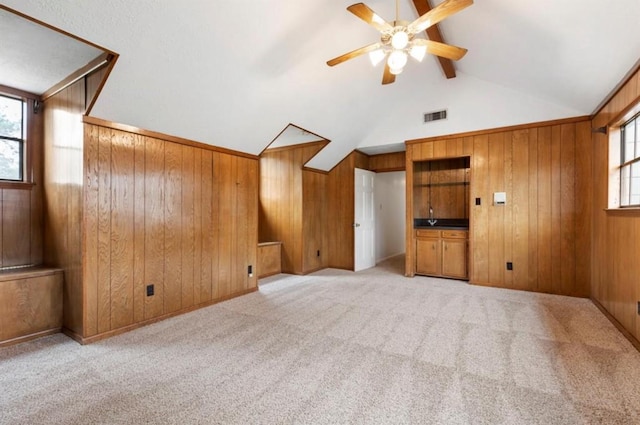 interior space featuring lofted ceiling with beams, wood walls, and a wealth of natural light