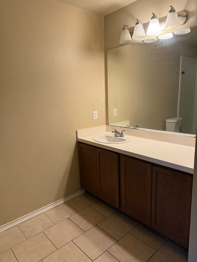 bathroom with a textured ceiling, tile patterned floors, vanity, and toilet