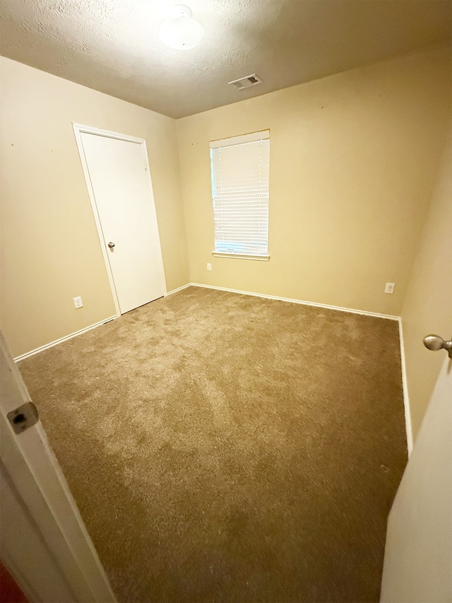 carpeted spare room featuring a textured ceiling