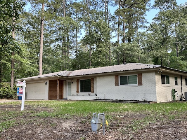 ranch-style home with an attached garage, metal roof, and brick siding