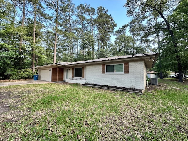 single story home featuring a front yard, brick siding, concrete driveway, an attached garage, and central air condition unit