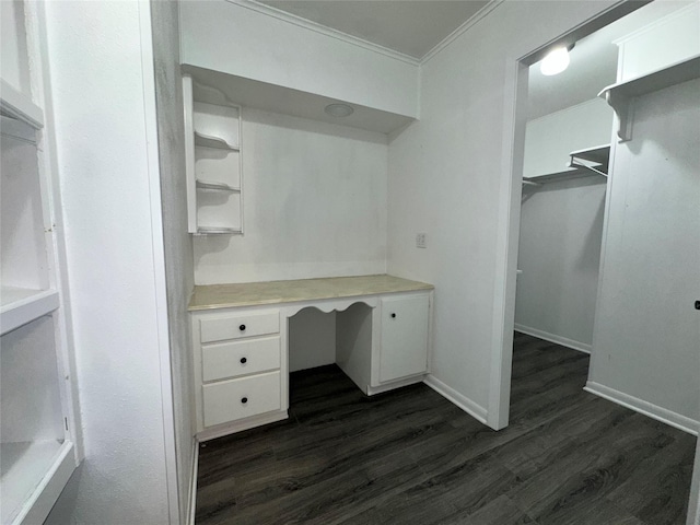 unfurnished office featuring crown molding, baseboards, dark wood finished floors, and built in study area
