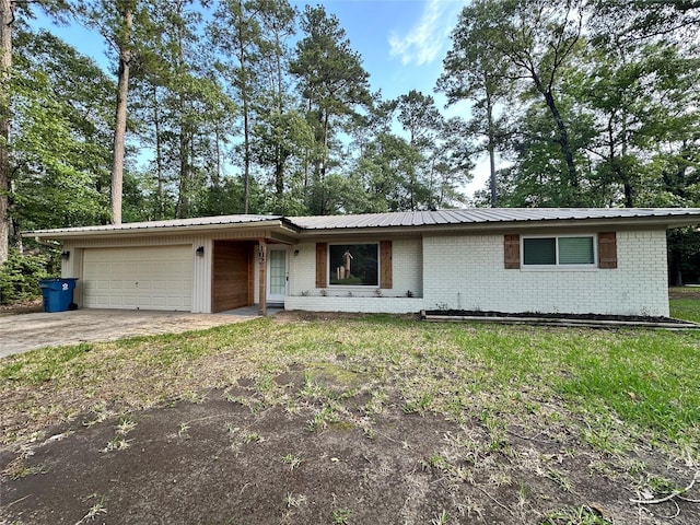 ranch-style home featuring an attached garage, driveway, metal roof, and brick siding