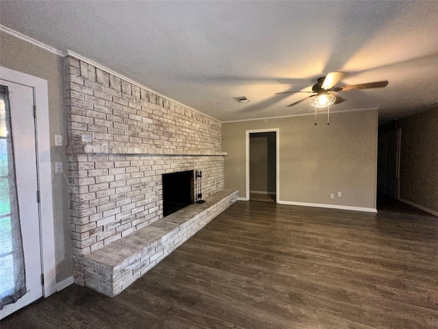 unfurnished living room with ceiling fan, a brick fireplace, baseboards, wood finished floors, and ornamental molding