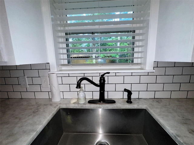 interior details featuring a sink, light stone countertops, and backsplash