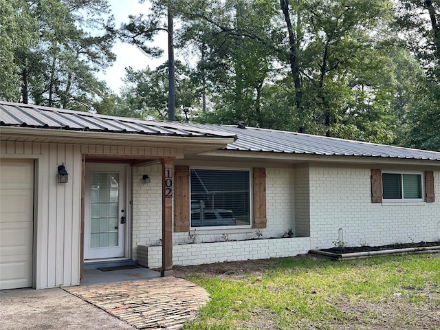 view of front of property with board and batten siding, brick siding, and metal roof
