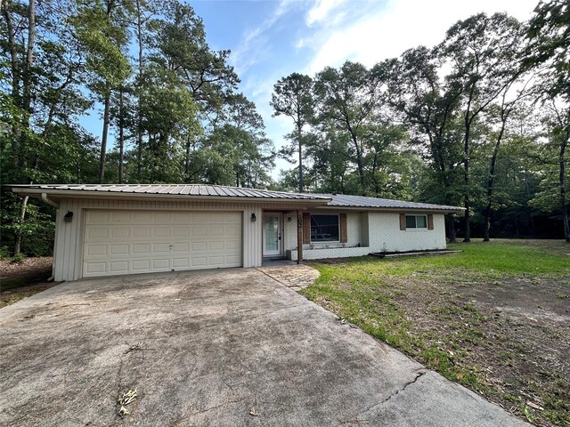 ranch-style home featuring an attached garage, metal roof, and concrete driveway