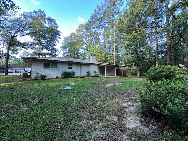 back of house with a yard, a chimney, and an attached carport