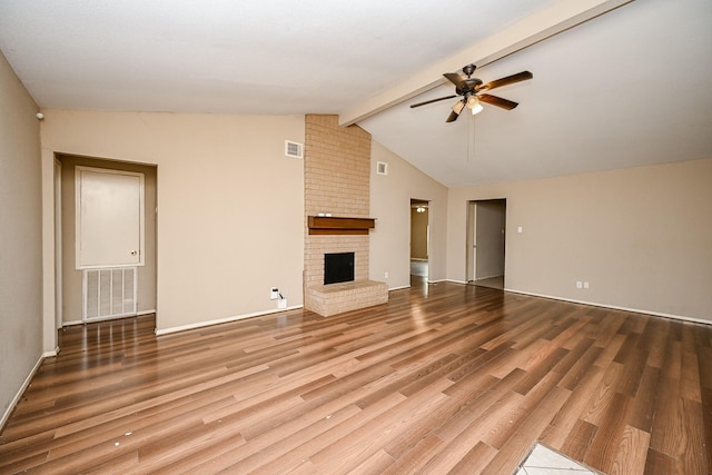 unfurnished living room featuring ceiling fan, lofted ceiling with beams, hardwood / wood-style flooring, and a brick fireplace