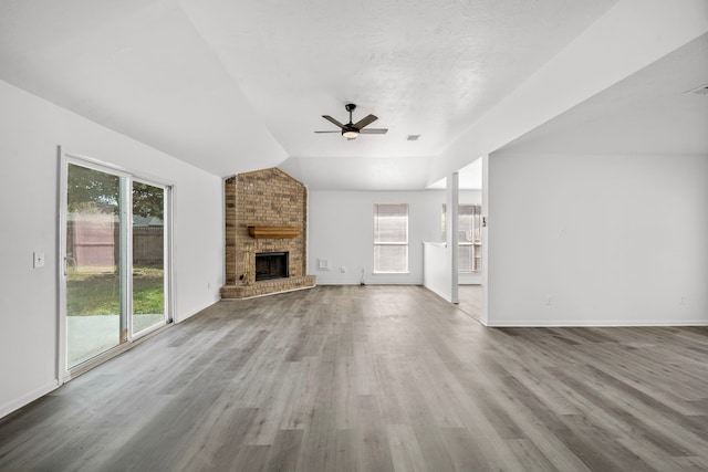 unfurnished living room with ceiling fan, a fireplace, light hardwood / wood-style floors, and lofted ceiling