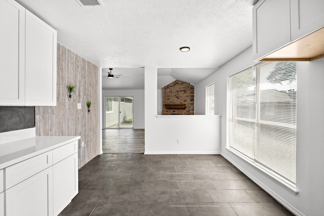 unfurnished dining area featuring a textured ceiling, ceiling fan, lofted ceiling, and wood walls