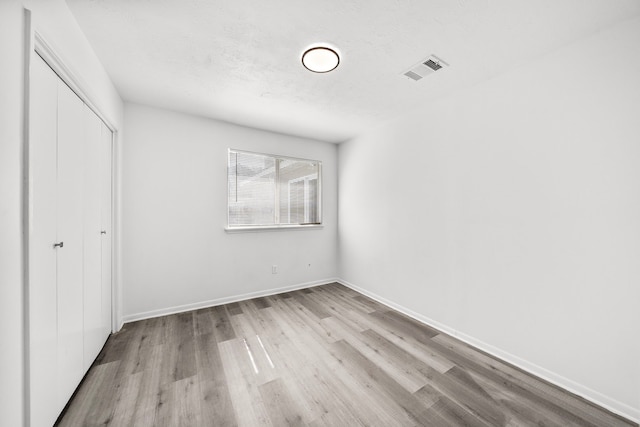 unfurnished bedroom with a closet, light hardwood / wood-style floors, and a textured ceiling