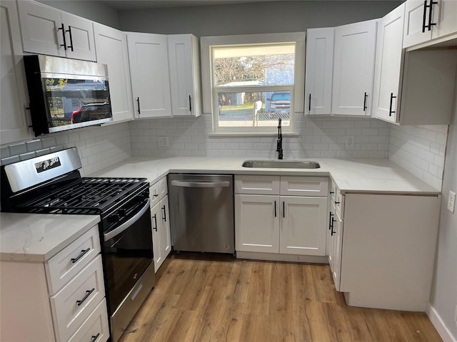 kitchen with appliances with stainless steel finishes, white cabinetry, and sink