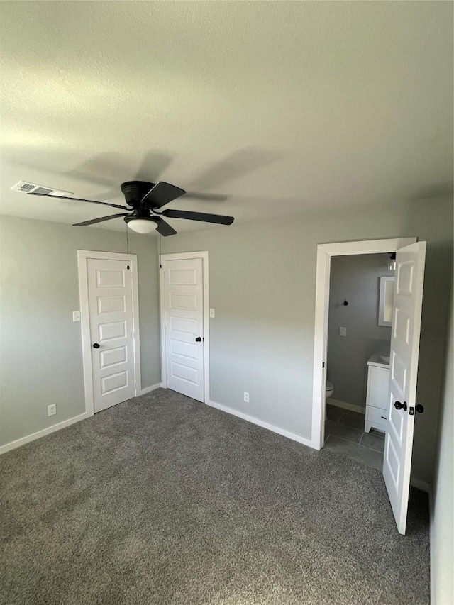 unfurnished bedroom featuring ceiling fan, connected bathroom, and dark colored carpet