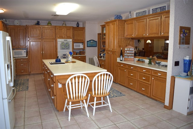 kitchen with white appliances, a kitchen island, and a breakfast bar area